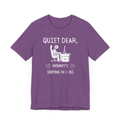 A flat image of a purple heather t-shirt that reads Quiet Dear, Mommy's Sniping Noobs in white text. The lower text is framed by two hearts, and the O's are in the shape of sniper scopes. In the center of the shirt is an image of a person at a desk with a gaming PC.