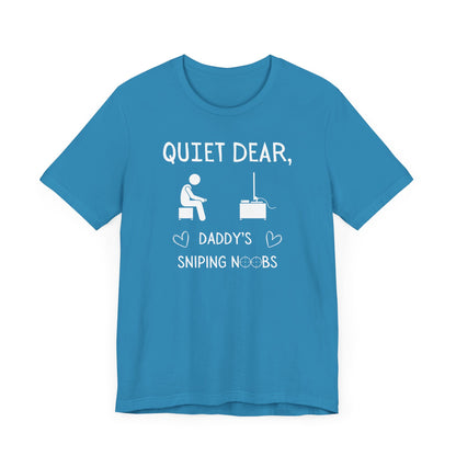 A flat image of an aqua t-shirt that reads Quiet Dear, Daddy's Sniping Noobs in white text. The lower text is framed by two hearts, and the O's are in the shape of sniper scopes. In the center of the shirt is an image of a person holding a controller sitting across from a TV.