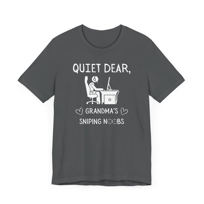 A flat image of a gray  t-shirt that reads Quiet Dear, Grandma's Sniping Noobs in white text. The lower text is framed by two hearts, and the O's are in the shape of sniper scopes. In the center of the shirt is an image of a person at a desk with a gaming PC.