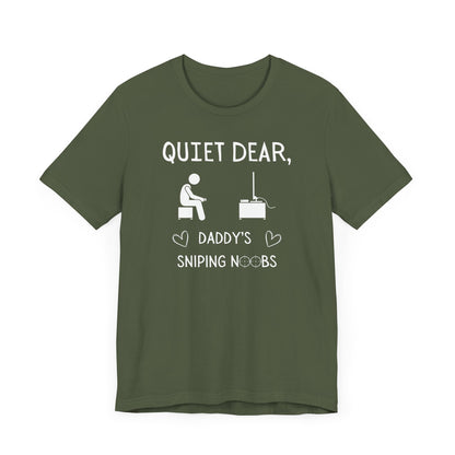 A flat image of a military green t-shirt that reads Quiet Dear, Daddy's Sniping Noobs in white text. The lower text is framed by two hearts, and the O's are in the shape of sniper scopes. In the center of the shirt is an image of a person holding a controller sitting across from a TV.